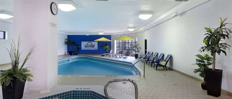 An indoor swimming pool area with lounge chairs and a sign for Days Inn.