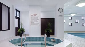 Un espace autour d’une piscine avec un panneau d’avertissement, une horloge et une porte portant l’inscription : « FONCTIONNEMENT DES PROPULSEURS PENDANT 1 MINUTE ».