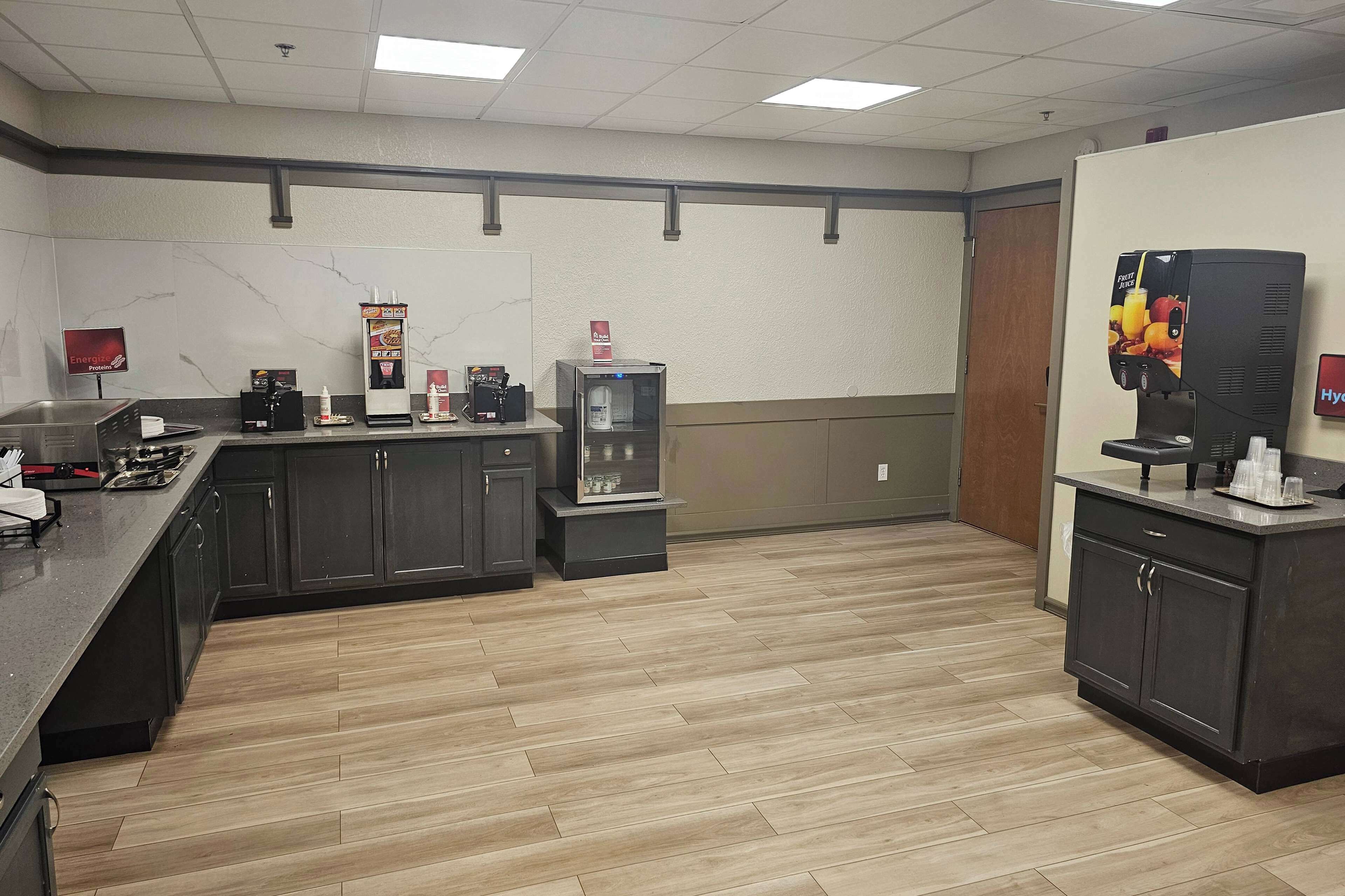 A spacious kitchen area with dark cabinets, a marble backsplash, and a coffee station.