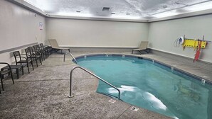 En swimmingpool med en kant som är klädd med kakel, ett metallräcke och flera solstolar.