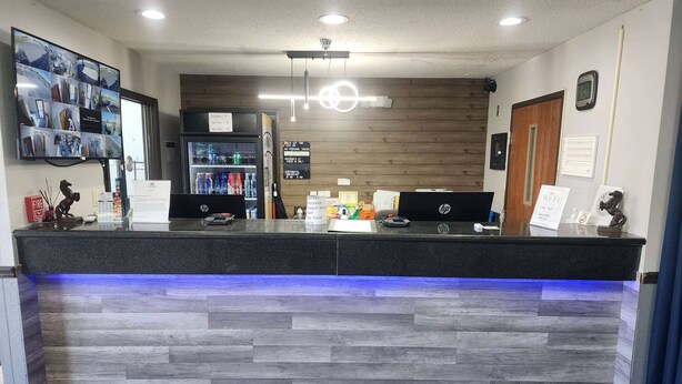 A reception desk with a digital display, a fire extinguisher, and a refrigerator. - Super 8 by Wyndham Galesburg (Galesburg)