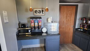 A compact kitchen with a microwave, coffee machine, and condiment dispensers. - Super 8 by Wyndham Galesburg (Galesburg)