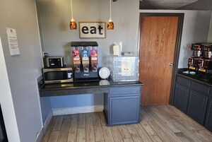 Cocina compacta con microondas, cafetera y dispensadores de condimentos.