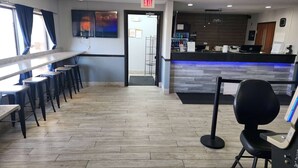 A hotel lobby with a reception desk, a bar area, and a seating section with tables and chairs. - Super 8 by Wyndham Galesburg (Galesburg)