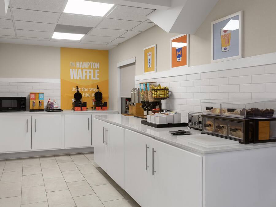 Una zona de cocina con una estación de waffles, microondas y diversos alimentos.
