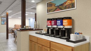 A coffee station with labeled dispensers for hot water, cream, dark roast, and light roast coffee.