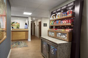 A hotel lobby with a snack bar, a reception desk, and a corridor leading to other areas.