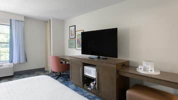 Habitación de hotel con cama, escritorio, televisión de pantalla plana, microondas y cafetera.