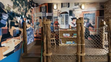 A wooden staircase with a rope barrier leading to a seating area with a colorful mural on the wall.