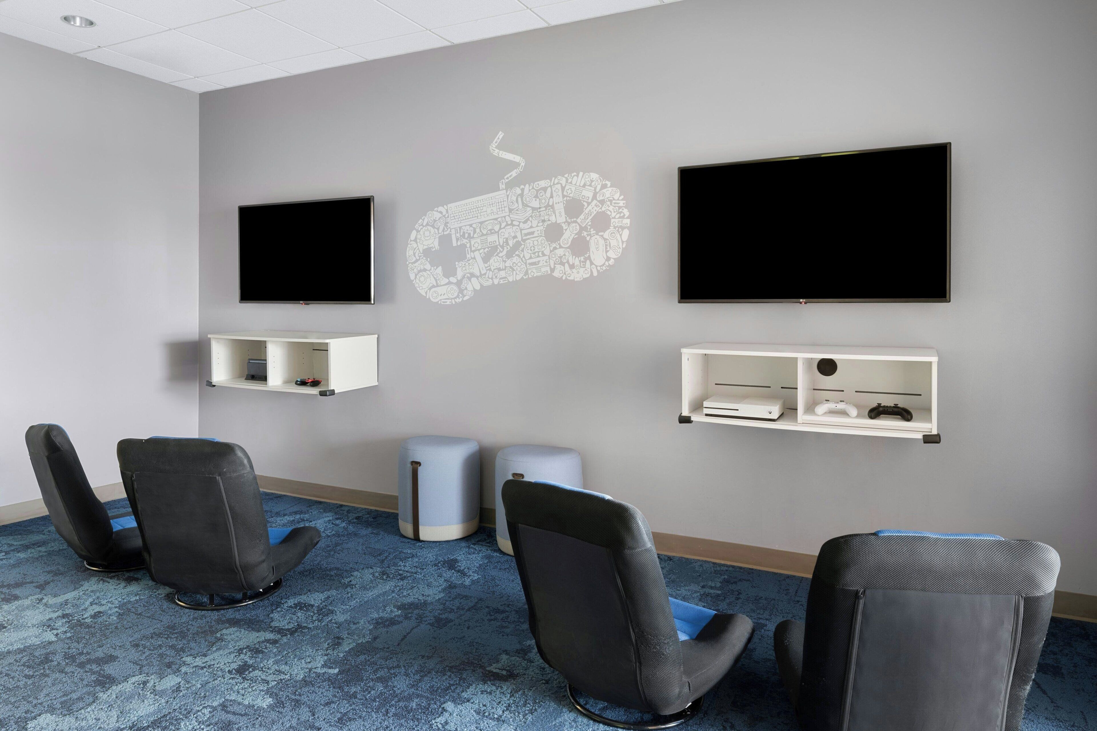 Een vergaderruimte met twee zwarte stoelen, een blauw tapijt en een whiteboard met een ontwerp van een gamecontroller.