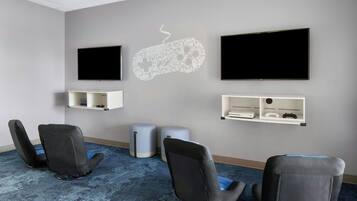 A conference room with two black chairs, a blue carpet, and a whiteboard with a game controller design.