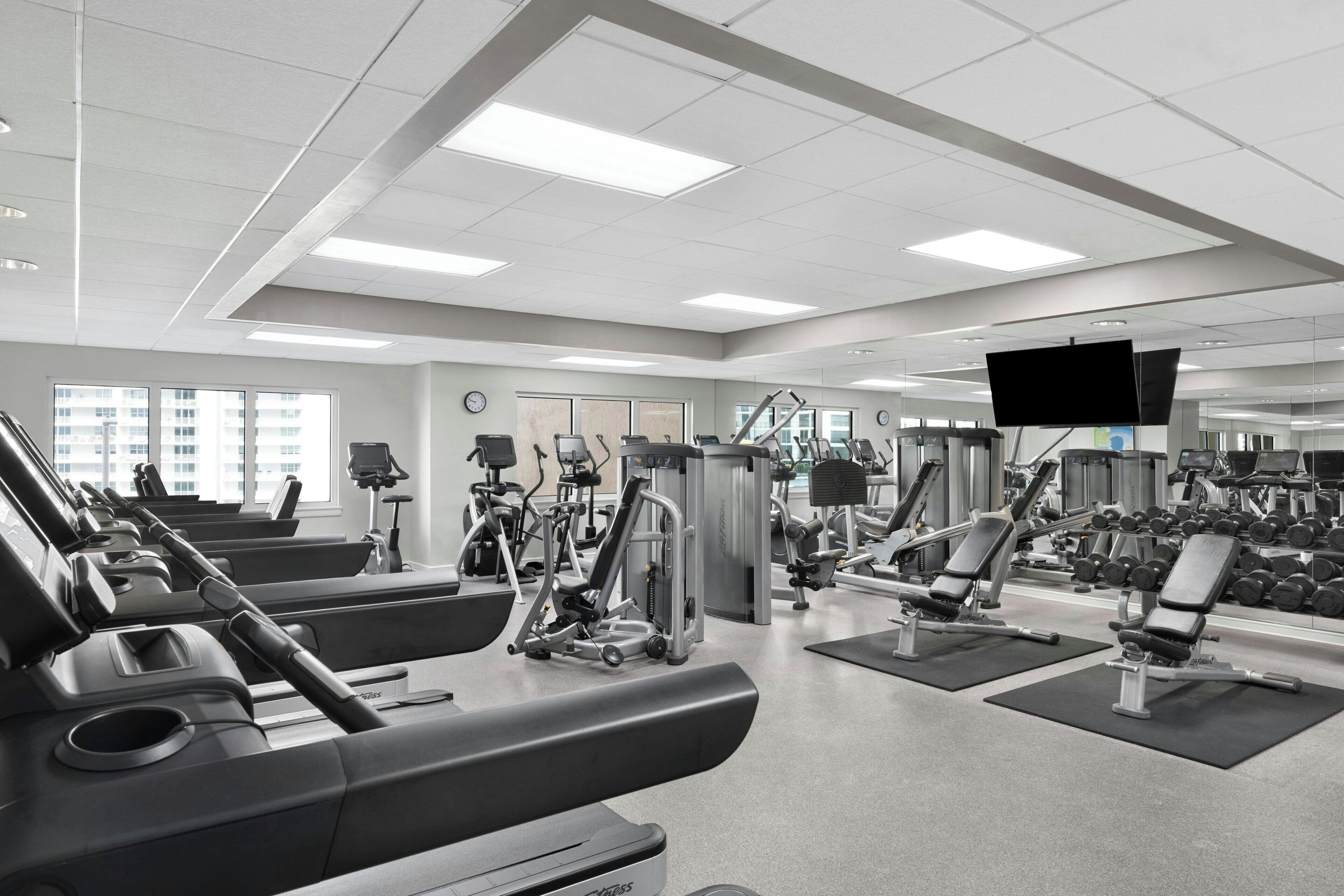 Un gimnasio moderno con cintas de correr, máquinas de pesas y mancuernas.