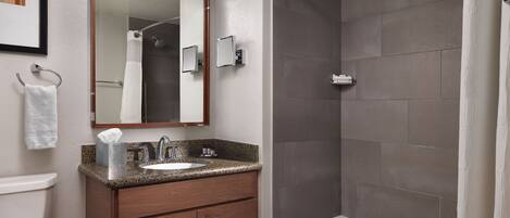 A bathroom with a sink, mirror, and shower.