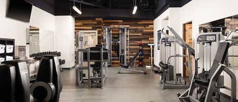 A gym with various exercise equipment, including treadmills, weight machines, and a rowing machine.