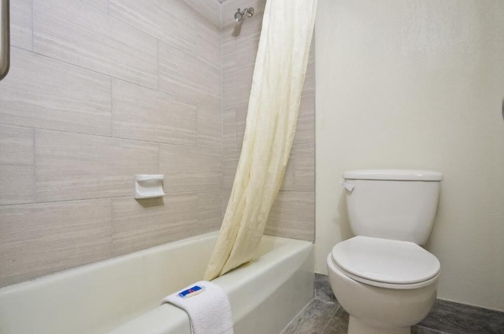 A bathroom with a bathtub, toilet, and shower curtain.