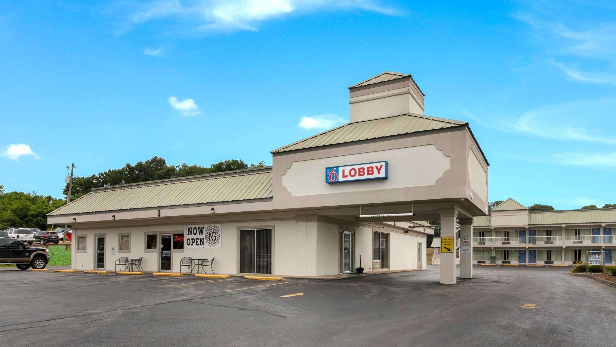 A building with a sign reading "Lobby" and a "NOW OPEN" sign.