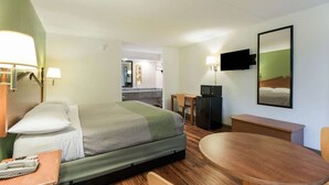Une chambre d’hôtel équipée d’un lit, d’un bureau, d’une chaise, d’une télévision et d’un miroir.