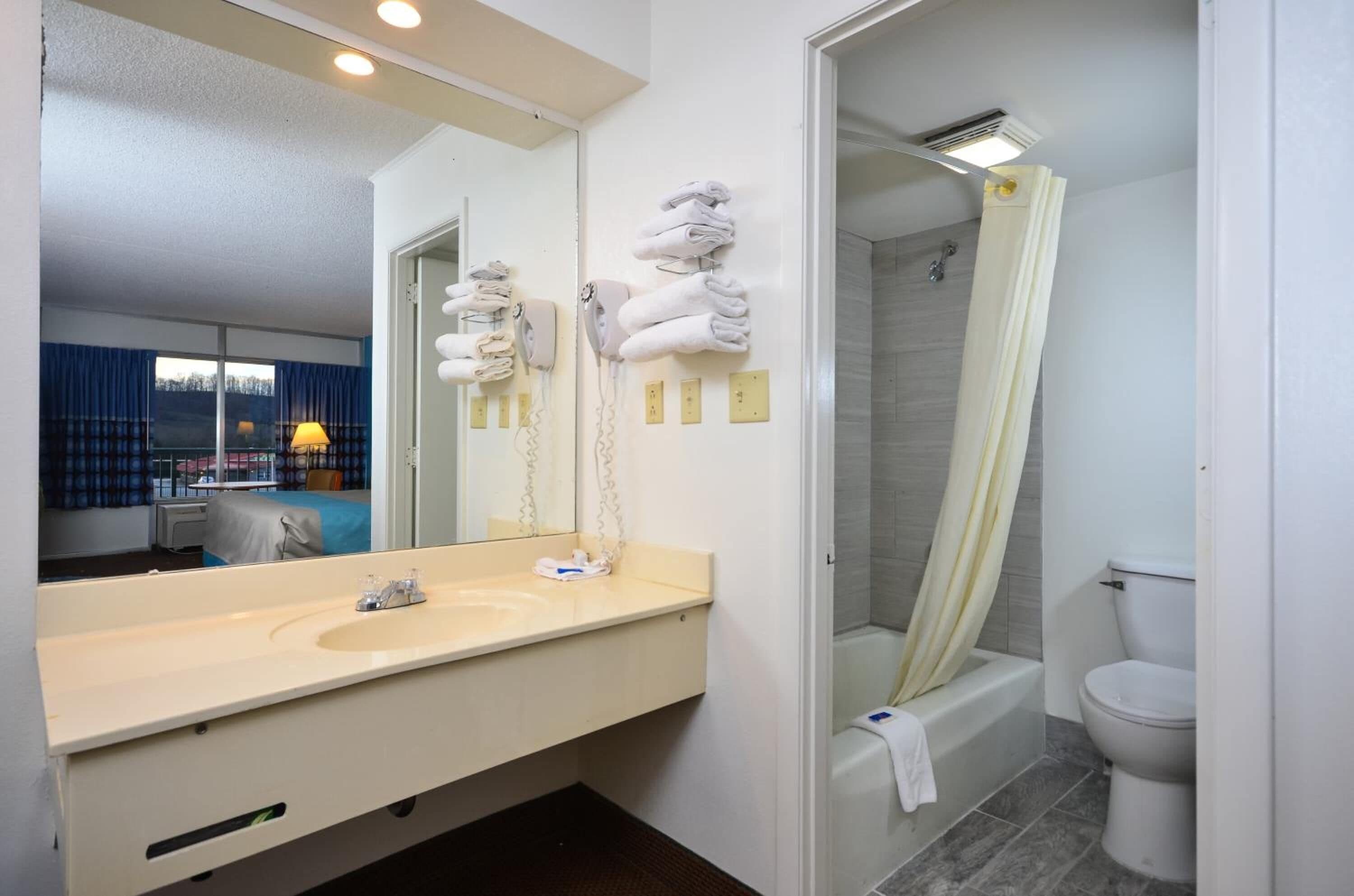 Un baño de hotel con un espejo grande, un lavabo, un inodoro y una ducha.
