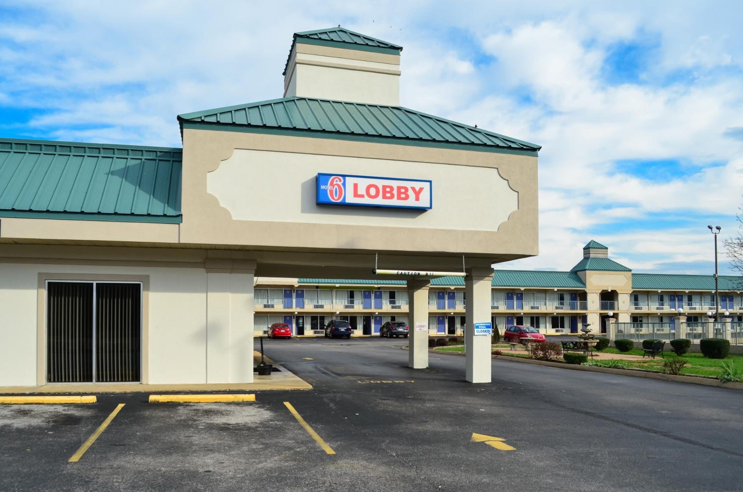 Un motel con un letrero que dice 'Lobby', varias habitaciones y un estacionamiento.