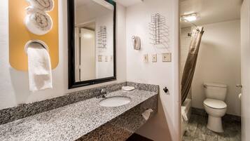 A bathroom with a granite sink, a large mirror, and a shower curtain.