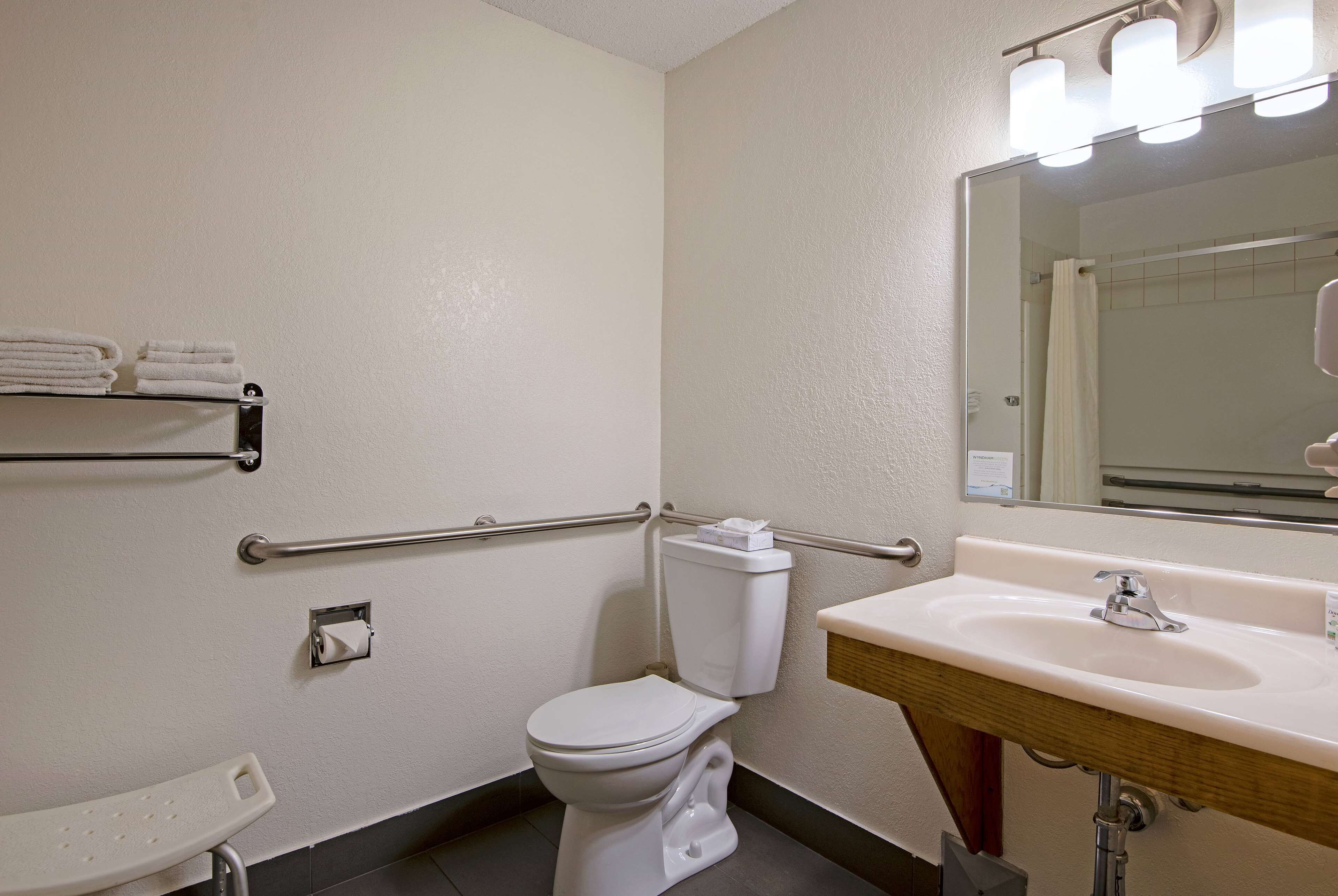 Une salle de bain équipée de toilettes, d’un lavabo et de barres d’appui.