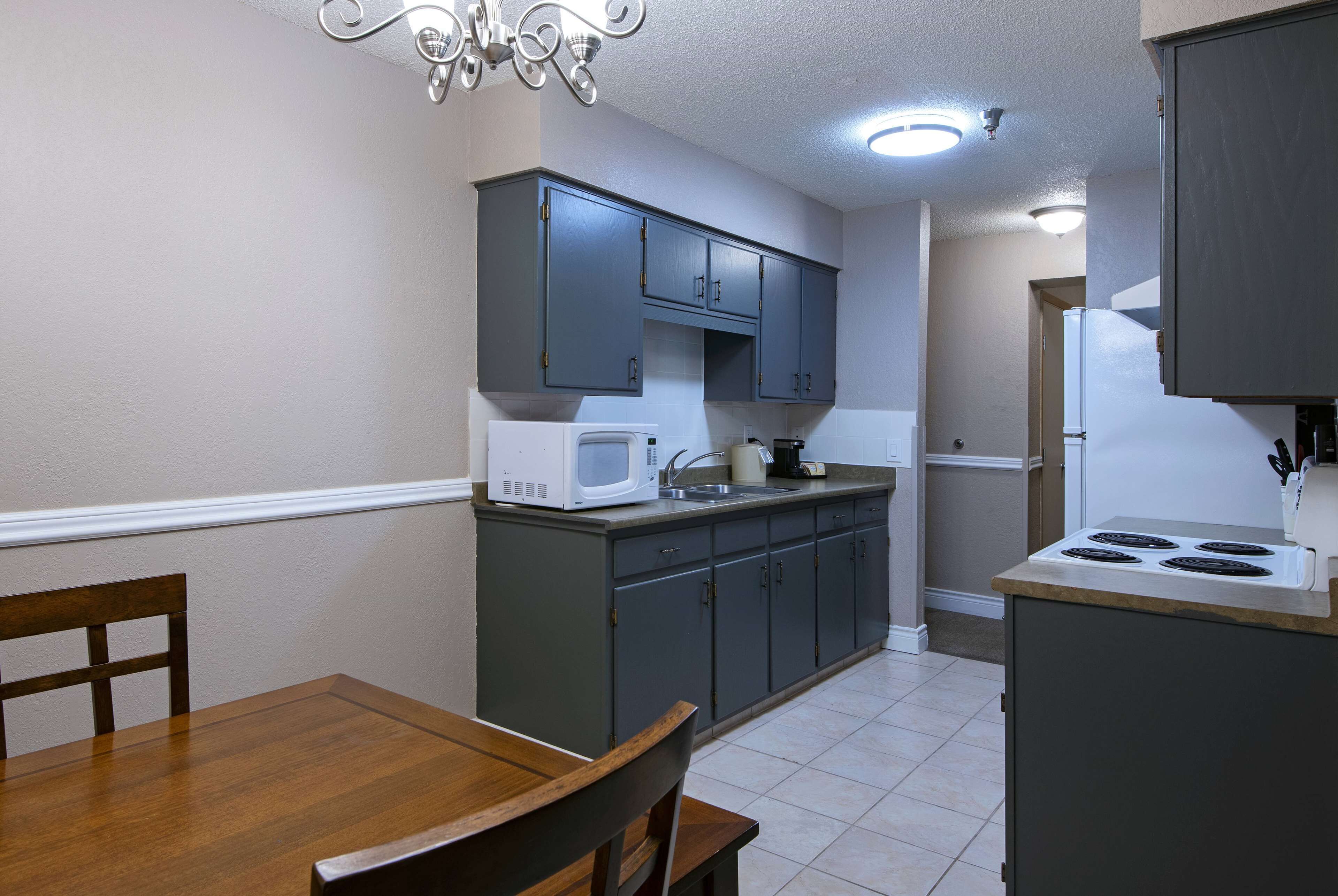 A compact kitchen with dark cabinets, a white microwave, and a stove.