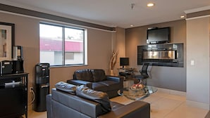 A modern living room with a sofa, coffee machine, and a flat-screen TV mounted on the wall. - Super 8 by Wyndham Kamloops On The Hill (Kamloops)