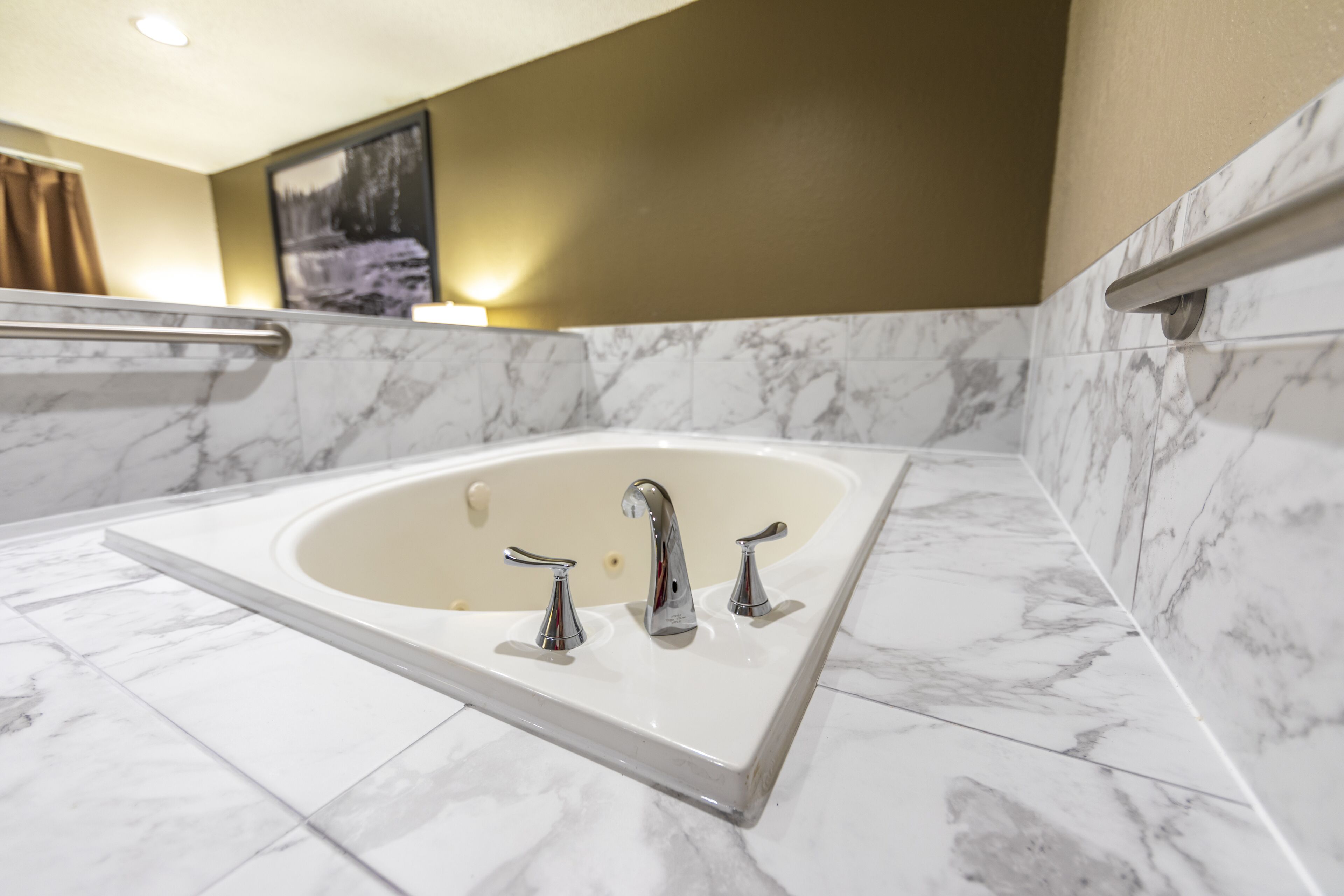 A bathroom with a marble sink, three faucets, and a bathtub.