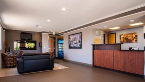A lobby with a reception desk, a seating area with a sofa and chairs, a television mounted on the wall, and a framed picture. - Super 8 by Wyndham Kamloops On The Hill (Kamloops)