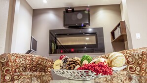 A living room with a sofa, a glass coffee table, and a flat-screen TV mounted on the wall. - Super 8 by Wyndham Kamloops On The Hill (Kamloops)