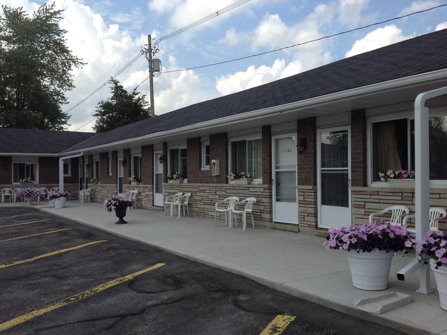 A motel with a row of rooms, outdoor seating, and flower planters.