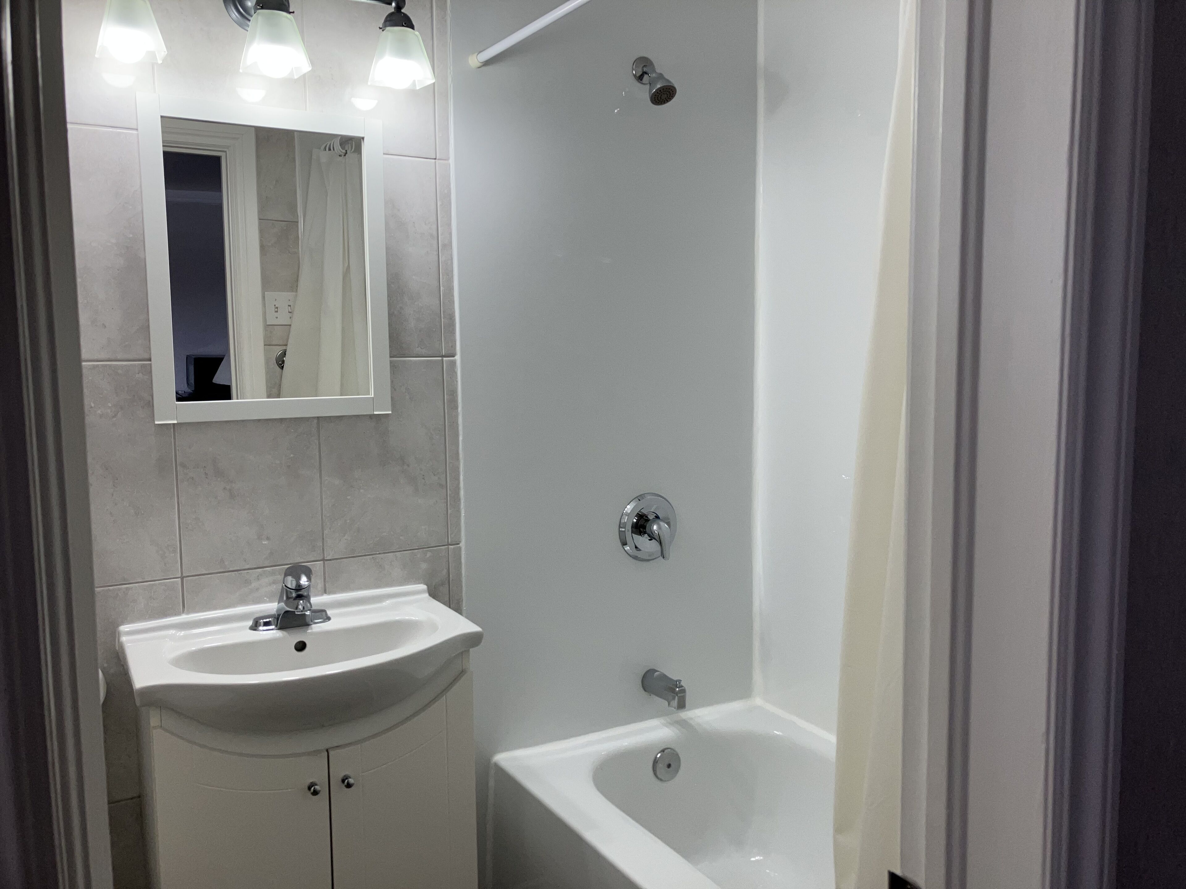 Een badkamer met een wastafel, spiegel en douche.
