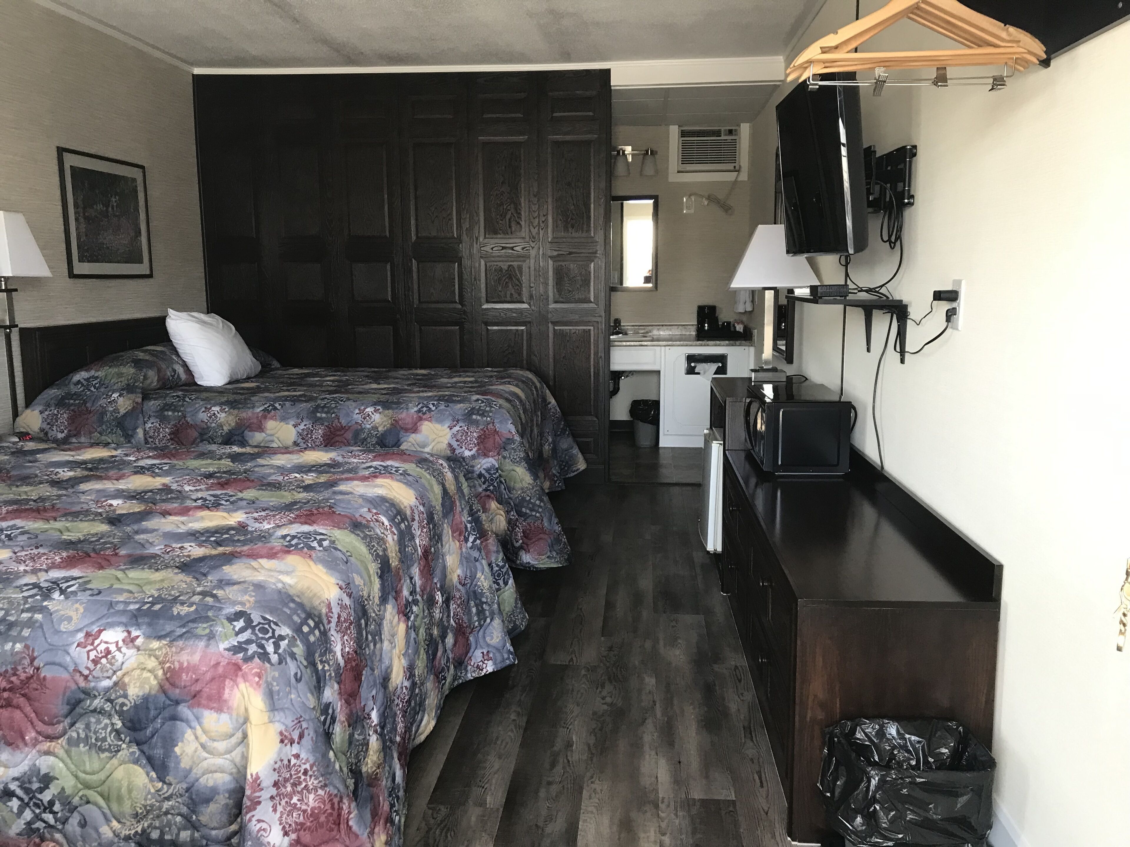 A bedroom with two beds, a desk, a television, and a wardrobe.