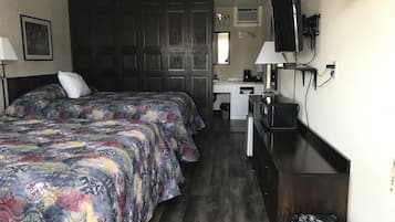 A bedroom with two beds, a desk, a television, and a wardrobe.
