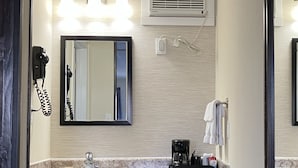 Un baño con lavamanos, espejo, toallero y secador de pelo.