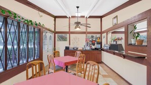 A dining area with wooden chairs and tables, a ceiling fan, and a view through large windows. - Knights Inn Battle Creek (Battle Creek)