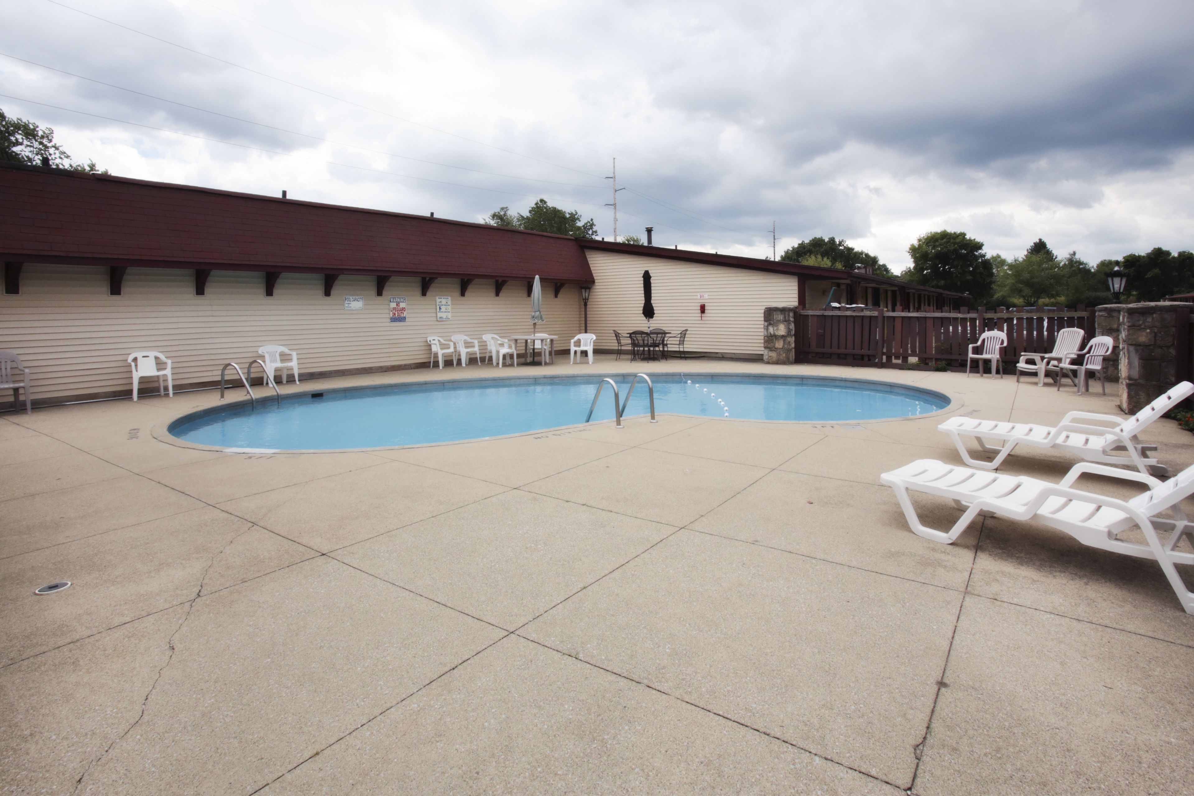 Piscina con sillones de descanso y una zona cubierta con mesas y sillas.