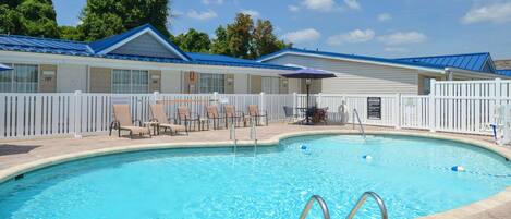 A swimming pool with lounge chairs and a fenced deck area.