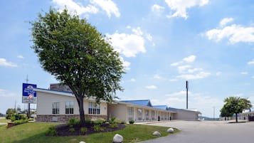 Simple, single-story hotel with a flat roof and large windows, set amidst a well-manicured lawn with large rocks.
