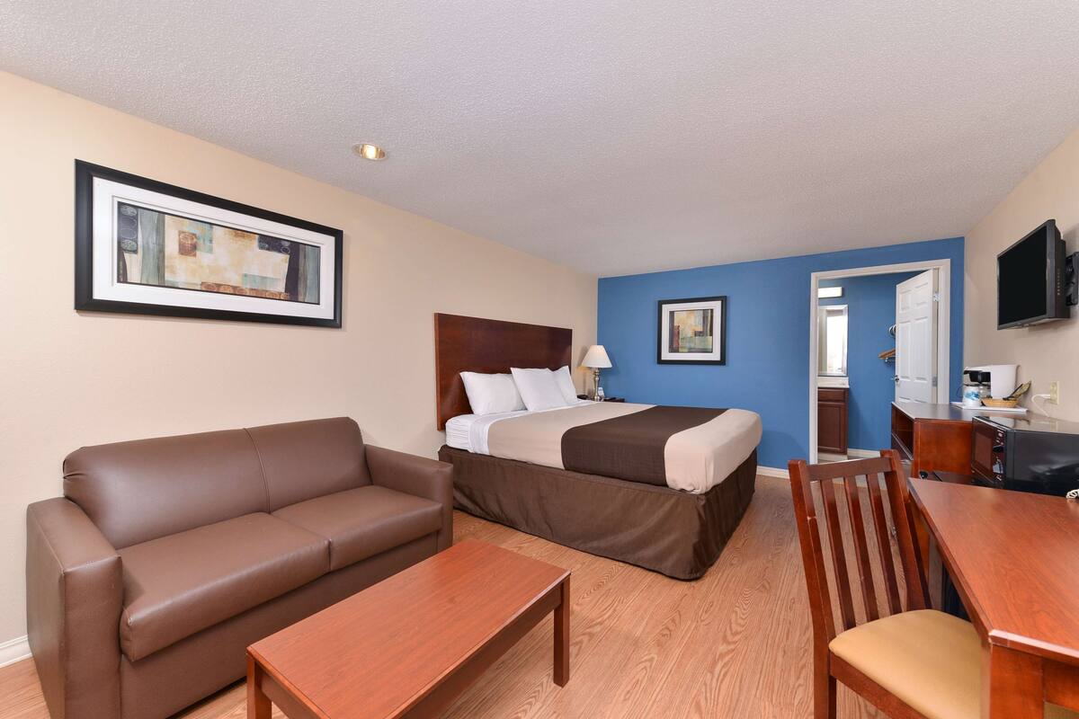 Una habitación de hotel con una cama, un sofá, una mesa de madera y un televisor.