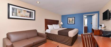 A hotel room with a bed, a sofa, a wooden table, and a TV.