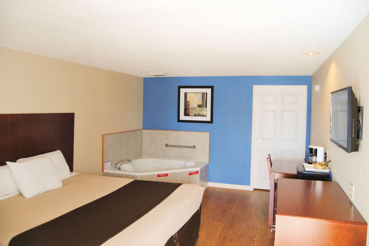 Una habitación de hotel con cama, bañera, escritorio y televisión.