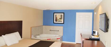 Una habitación de hotel con cama, bañera, escritorio y televisión.