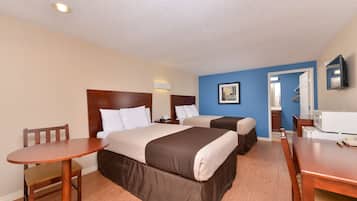A hotel room with two beds, a wooden table, a chair, a desk, and a television.
