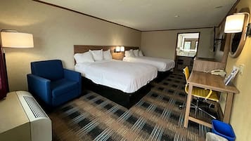 A hotel room with two beds, a desk with a chair, a lamp, and a trash bin.