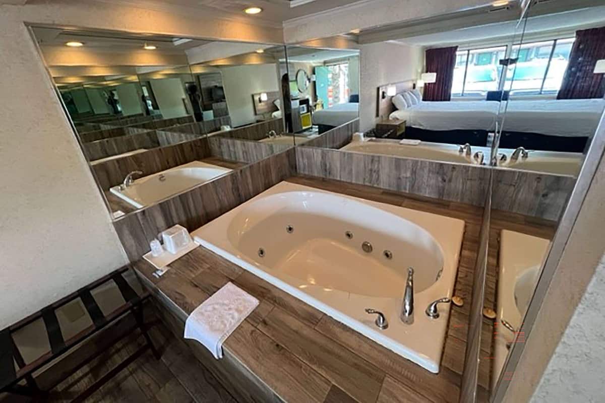 A modern bathroom with a large bathtub, two sinks, and a mirror.