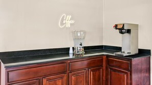 Un comptoir de cuisine avec une machine à café et une verseuse en verre transparent.
