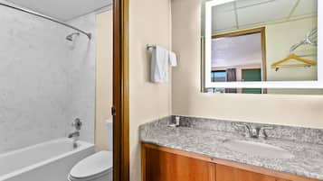 A bathroom with a bathtub, toilet, sink, and wooden vanity.