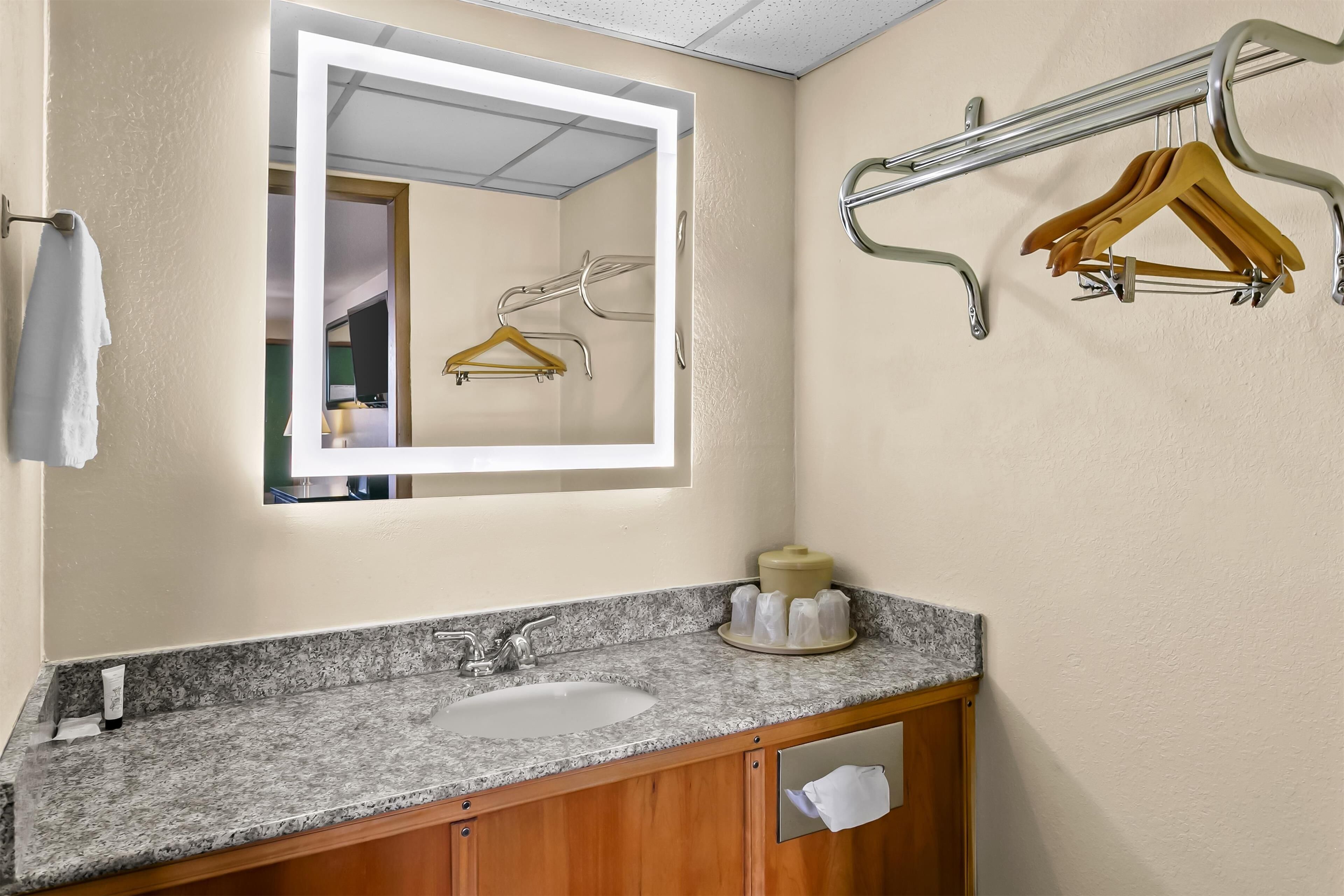 Een badkamer met een wastafel met granieten blad, een spiegel en een handdoekhouder.