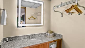 Een badkamer met een wastafel met granieten blad, een spiegel en een handdoekhouder.